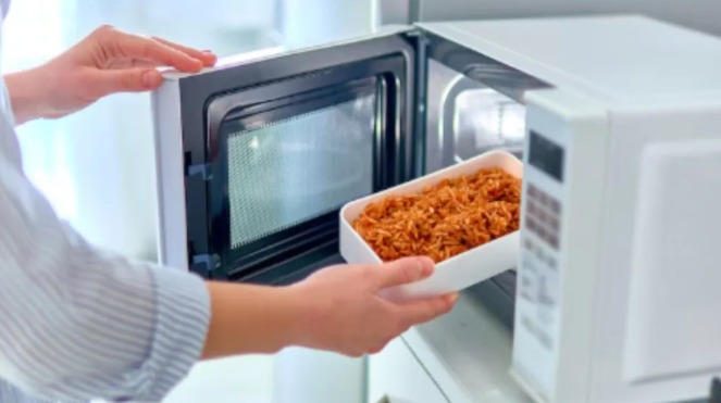 "Leftover food in containers being reheated in a microwave during monsoon"